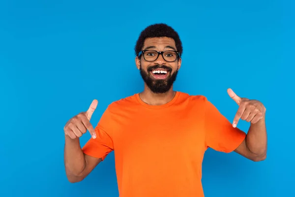 Heureux homme afro-américain pointant avec les doigts isolés sur bleu — Photo de stock