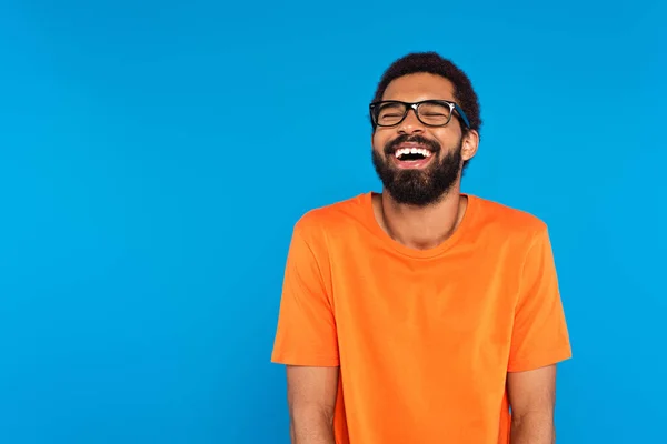 Africano americano hombre en gafas riendo aislado en azul — Stock Photo