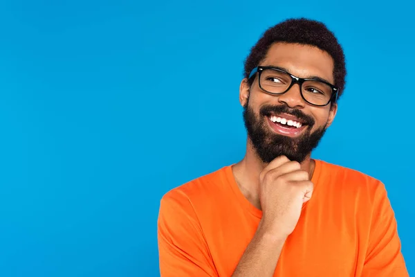 Усміхнений афроамериканський чоловік в окулярах дивиться ізольовано на синьому — стокове фото