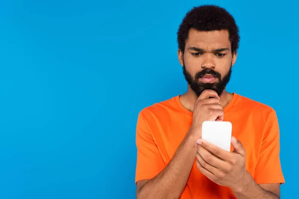 Pensativo homem americano africano usando smartphone isolado em azul — Fotografia de Stock