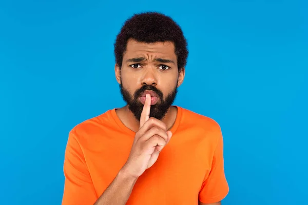 Barbudo afroamericano hombre mostrando silencio signo aislado en azul - foto de stock