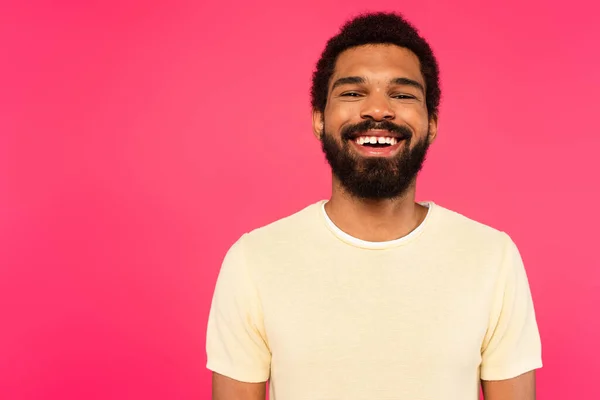 Веселий і бородатий афроамериканський чоловік посміхається ізольовано на рожевому — стокове фото