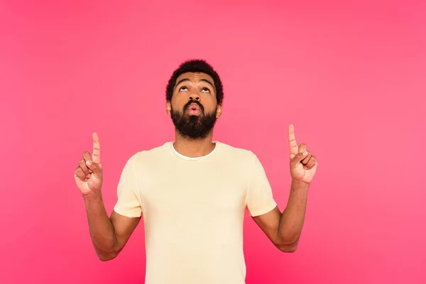 Barbudo hombre afroamericano sonriendo mientras señala con los dedos aislados en rosa - foto de stock