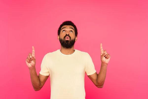 Homem americano africano barbudo sorrindo enquanto apontava com os dedos isolados em rosa — Fotografia de Stock