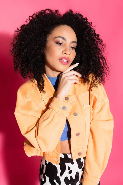Dreamy african american woman in crop top and jacket on pink — Stock Photo