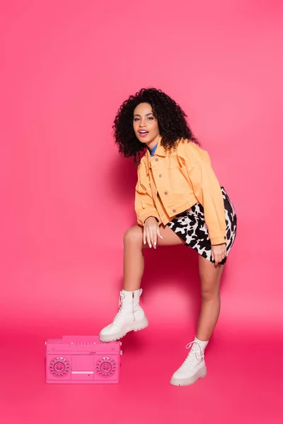 Full length of african american woman leaning on retro boombox on pink — Stock Photo