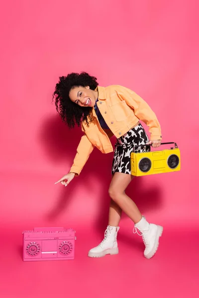 Full length of happy african american woman pointing at boombox on pink — Stock Photo