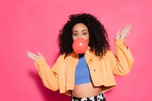 Confuse femme afro-américaine soufflant chewing-gum sur rose — Photo de stock