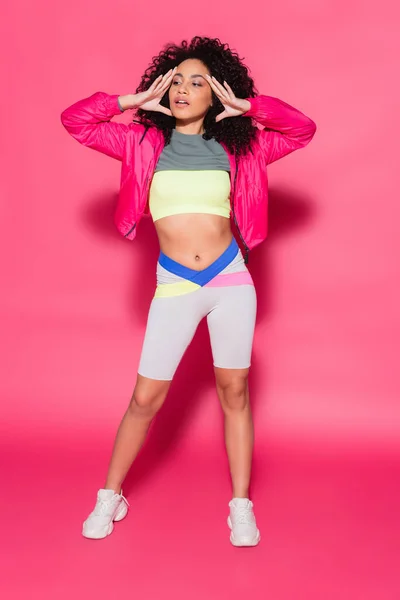Full length of sporty and curly african american woman posing on pink — Stock Photo