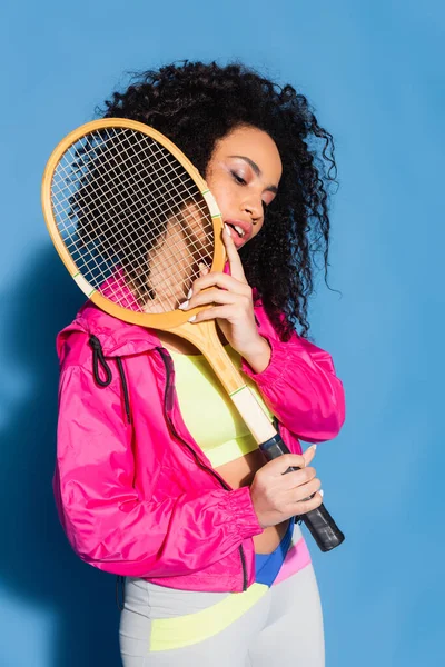 Junge Afroamerikanerin posiert mit Tennisschläger auf blau — Stockfoto