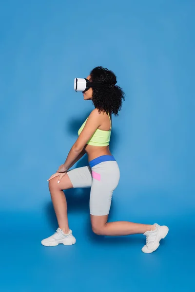 Pleine longueur de souriante femme afro-américaine en vr casque d'exercice sur bleu — Photo de stock