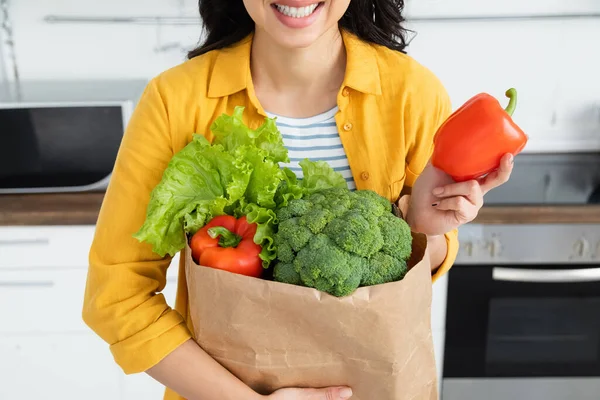 Abgeschnittene Ansicht einer glücklichen Frau, die eine Papiertüte mit Lebensmitteln hält — Stockfoto