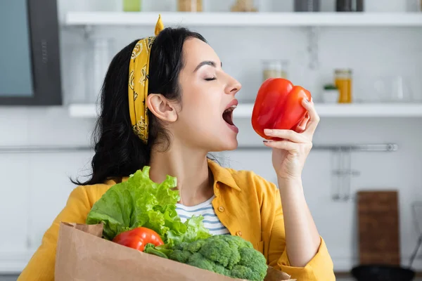 Young brunette woman biting red bell pepper — Stock Photo