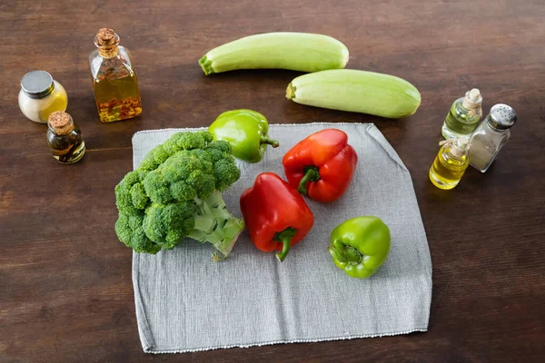 Top view of fresh vegetables on cloth napkin near bottles with oil on kitchen table — Stock Photo