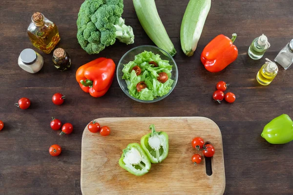 Top view of sliced green bell pepper on wooden chopping board near ripe vegetables — Stock Photo