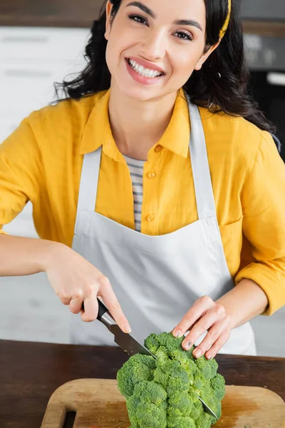 Happy brunette woman cutting green broccoli — Stock Photo