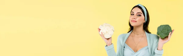 Pregnant woman with cauliflower and broccoli looking at camera isolated on yellow, banner — Stock Photo