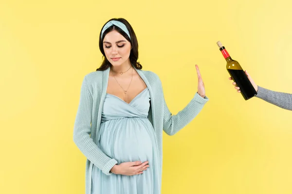 Молода вагітна жінка відмовляється від червоного вина ізольовано на жовтому — стокове фото