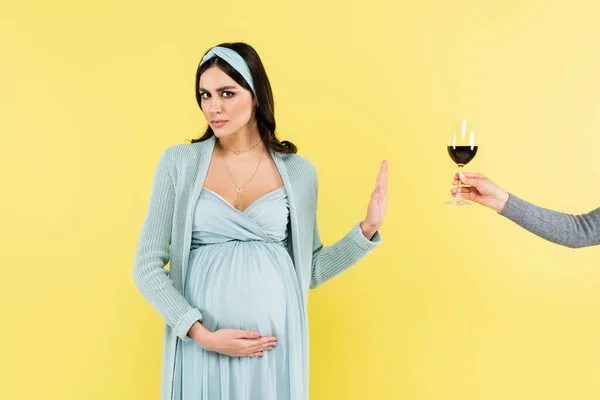 Pregnant woman showing stop gesture near wine glass isolated on yellow — Stock Photo