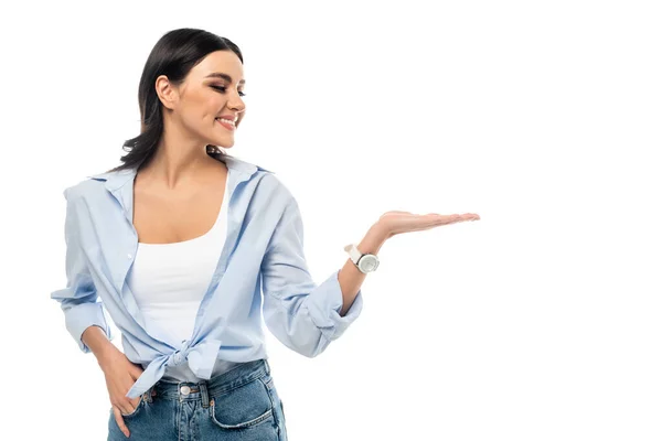 Smiling woman pointing with hand while standing with hand in pocket isolated on white — Stock Photo