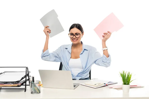 Раздраженная деловая женщина, держащая папки, сидя рядом с ноутбуком изолированы на белом — стоковое фото