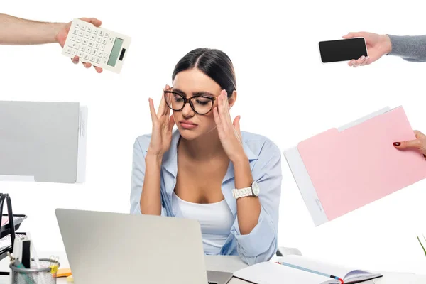 Exhausted businesswoman touching head at workplace near people with documents isolated on white — Stock Photo