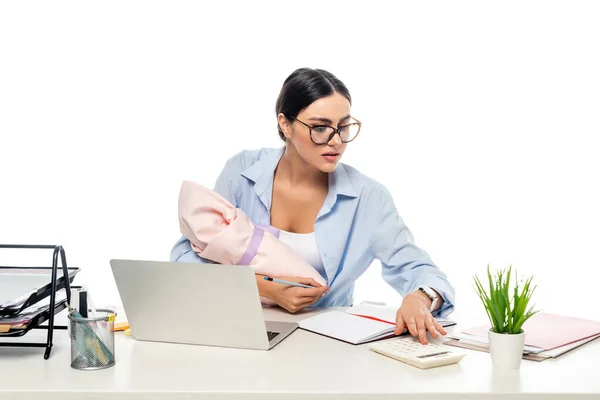 Jovem mãe segurando bebê recém-nascido enquanto trabalhava perto de laptop isolado no branco — Fotografia de Stock