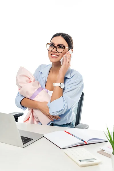 Mujer de negocios feliz sosteniendo niño bebé mientras habla en el teléfono inteligente en el lugar de trabajo aislado en blanco - foto de stock