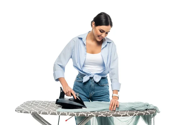 Feliz ama de casa sonriendo mientras plancha ropa aislada en blanco - foto de stock