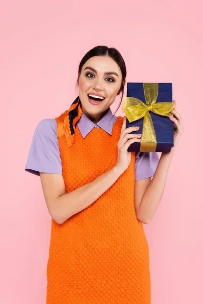 Amazed woman looking at camera while holding present isolated on pink — Stock Photo