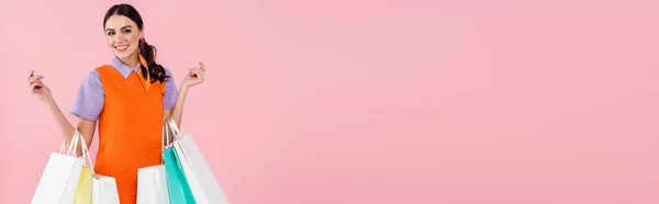 Mulher alegre com sacos de compras sorrindo para a câmera isolada em rosa, banner — Fotografia de Stock