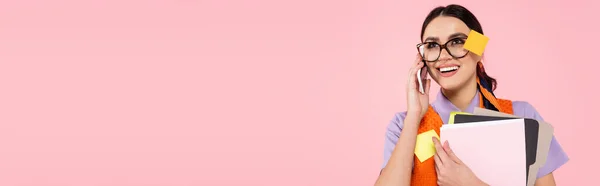 Zufriedene Geschäftsfrau hält Ordner in der Hand und telefoniert isoliert auf rosa Banner — Stockfoto