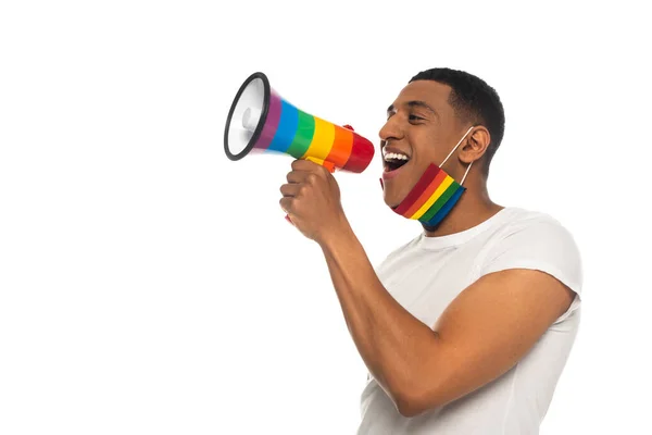 Hombre afroamericano con colores lgbt máscara médica gritando en megáfono aislado en blanco - foto de stock