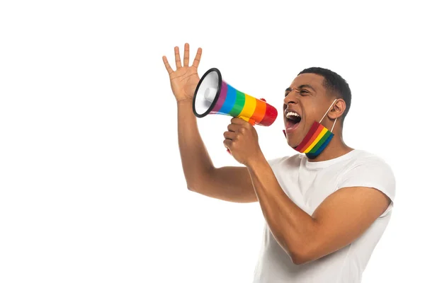 Hombre afroamericano con máscara médica en colores lgbt gritando en altavoz aislado en blanco - foto de stock