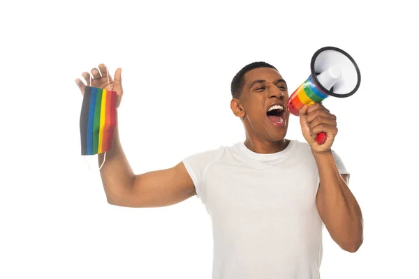 African american man holding lgbt colors medical mask while screaming in megaphone isolated on white — Stock Photo