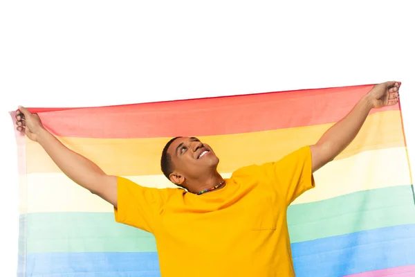 Hombre afroamericano feliz sosteniendo bandera lgbt mientras mira hacia arriba aislado en blanco - foto de stock