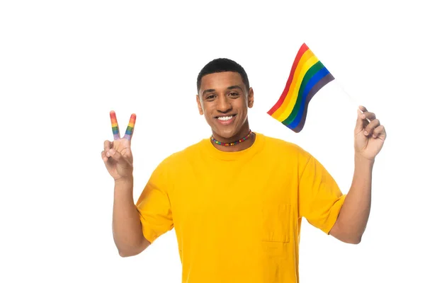 Hombre afroamericano sosteniendo bandera lgbt y mostrando gesto de victoria aislado en blanco - foto de stock