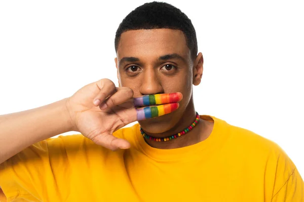 Homme afro-américain couvrant la bouche avec des doigts peints en couleurs lgbt isolé sur blanc — Photo de stock