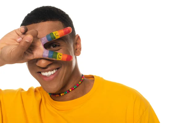 Smiling african american man showing peace sign with fingers painted in lgbt colors isolated on white — Stock Photo