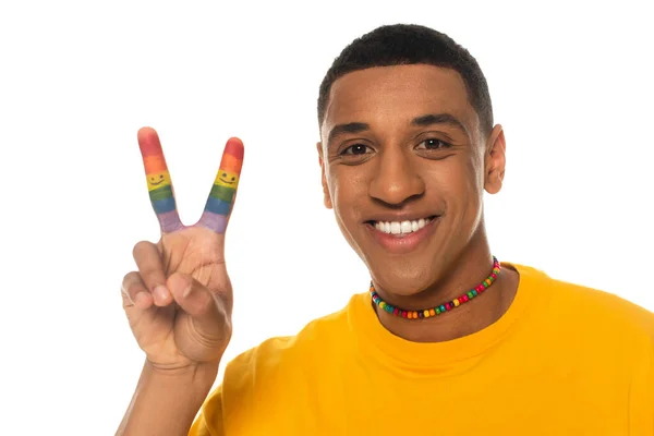 Homme afro-américain joyeux avec les doigts peints dans des couleurs lgbt montrant geste de paix isolé sur blanc — Photo de stock