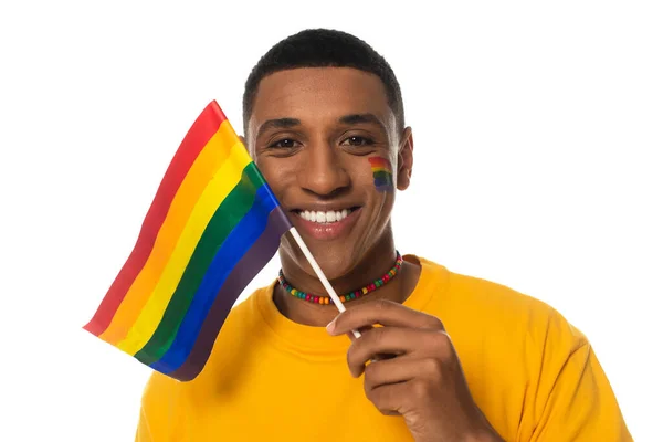 Щасливий афроамериканський чоловік з маленьким прапором lgbt дивиться на камеру ізольовано на білому — стокове фото
