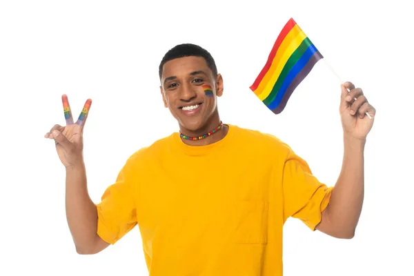 Hombre afroamericano feliz sosteniendo bandera lgbt y mostrando signo de victoria aislado en blanco - foto de stock