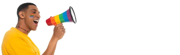 African american man with lgbt flag painted on face shouting in loudspeaker isolated on white, banner — Stock Photo