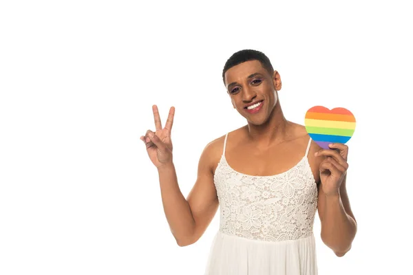 Smiling african american gay man holding lgbt colors paper heart and showing peace sign isolated on white — Stock Photo