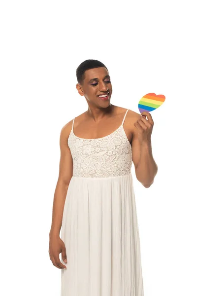 Joyful african american transgender man in dress holding lgbt colors paper heart isolated on white — Stock Photo