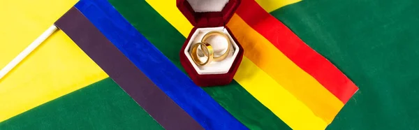 Vista superior da bandeira lgbt e caixa de jóias com anéis de casamento em cores do arco-íris fundo, banner — Fotografia de Stock