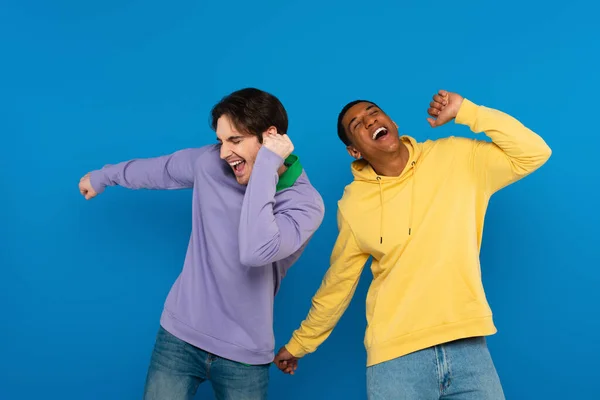 Feliz jovem afro-americano dançando com amigo isolado em azul — Fotografia de Stock
