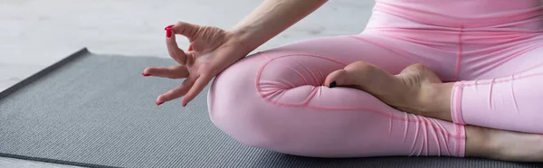 Visión parcial de la mujer descalza meditando en pose de loto, bandera - foto de stock