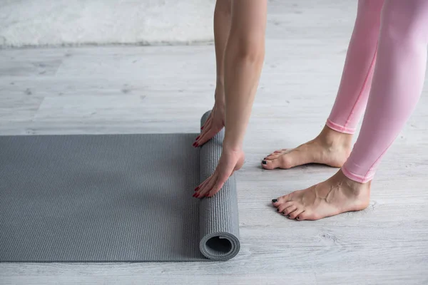 Cropped view of barefoot woman unrolling yoga mat at home — Stock Photo