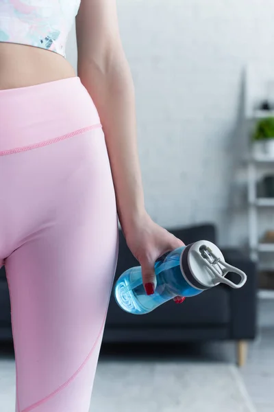 Частичный вид спортивной женщины в леггинсах, держащей спортивную бутылку — стоковое фото